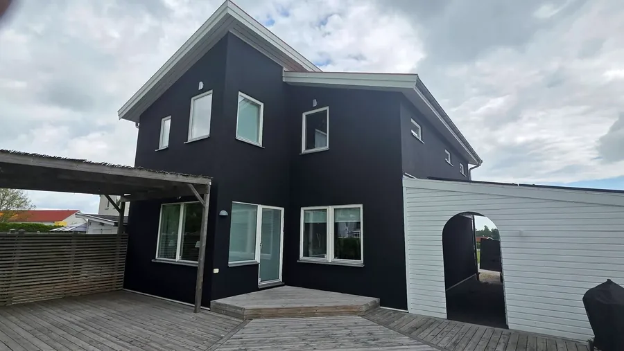 Svartmålad villa med carport